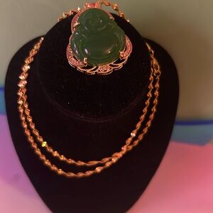 A gold neckless with a green cute chubby Buddha on the bottom of the neckless